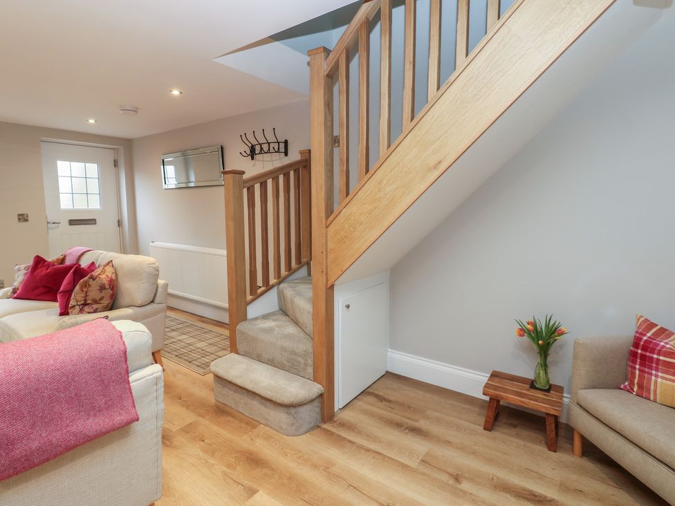 A living room with a staircase and sofa at Brooklyn Cottage in Kirkby Malzeard