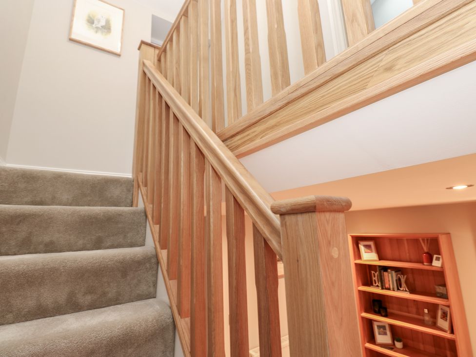 A staircase with wooden railing and carpet at Brooklyn Cottage in Kirkby Malzeard