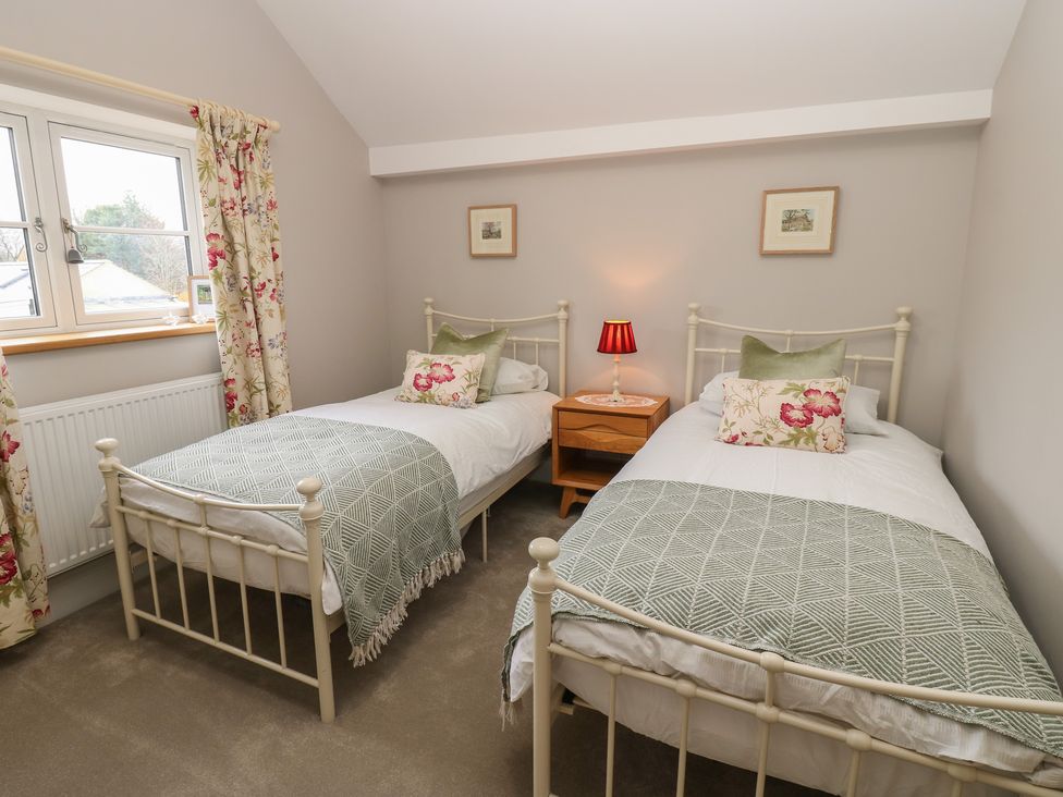 A bedroom with two single beds and a bedside table at Brooklyn Cottage in Kirkby Malzeard
