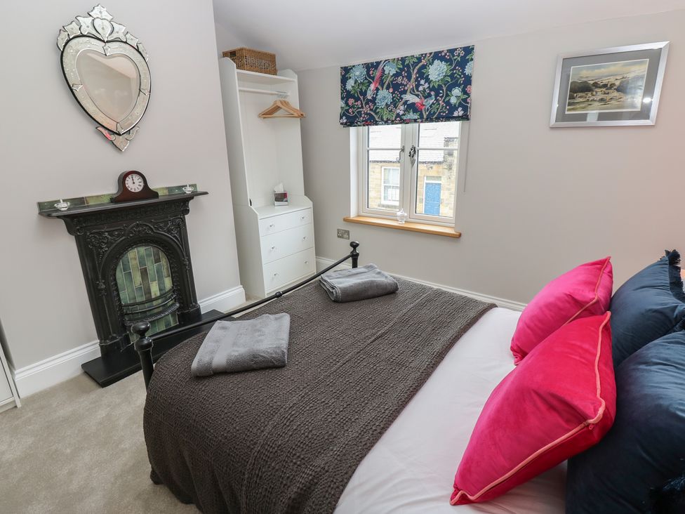 A bedroom with a bed and a fireplace at Brooklyn Cottage in Kirkby Malzeard