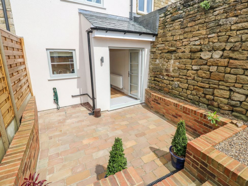 An outdoor area with a patio and stone wall at Brooklyn Cottage, Kirkby Malzeard