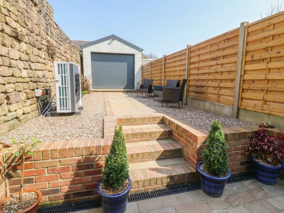 A garden with a patio and lounge chairs at Brooklyn Cottage in Kirkby Malzeard