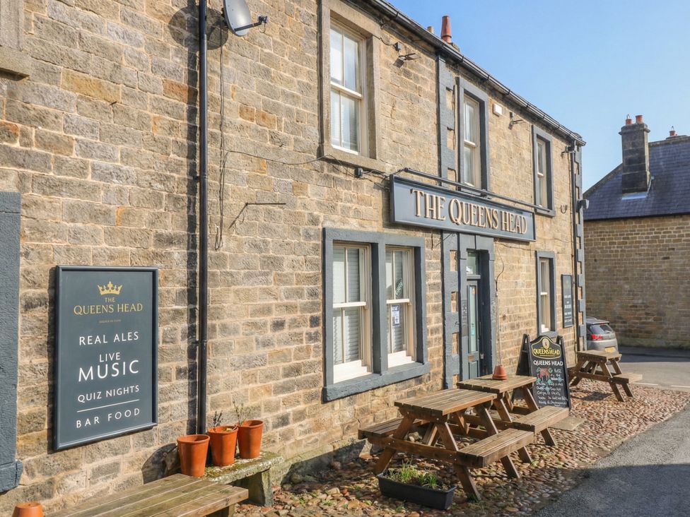 An exterior view of The Queens Head pub with outdoor seating in Kirkby Malzeard
