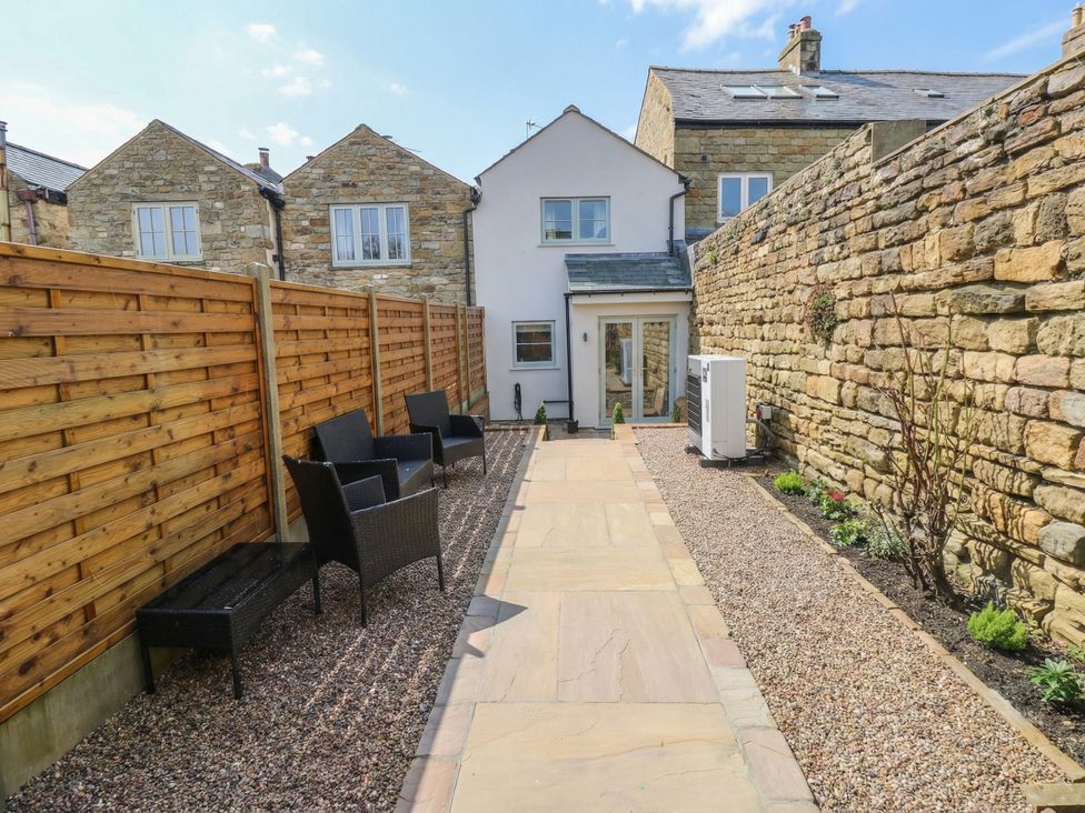 A garden with chairs and a pathway at Brooklyn Cottage in Kirkby Malzeard