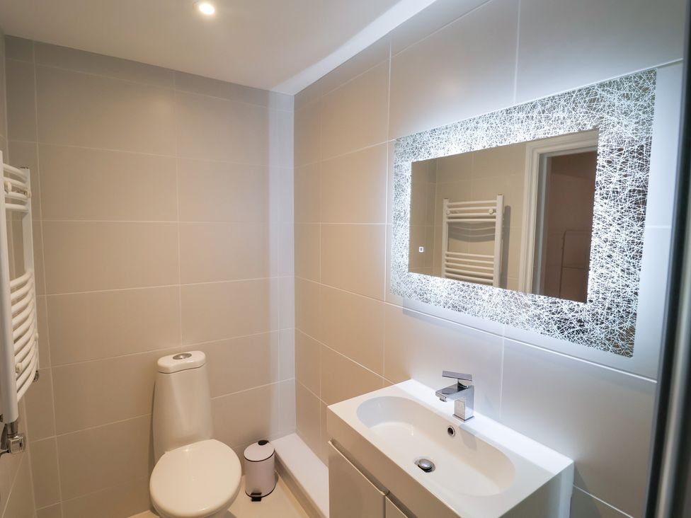 A bathroom with a toilet, sink, and mirror at Three Ways in South Lopham near Garboldisham