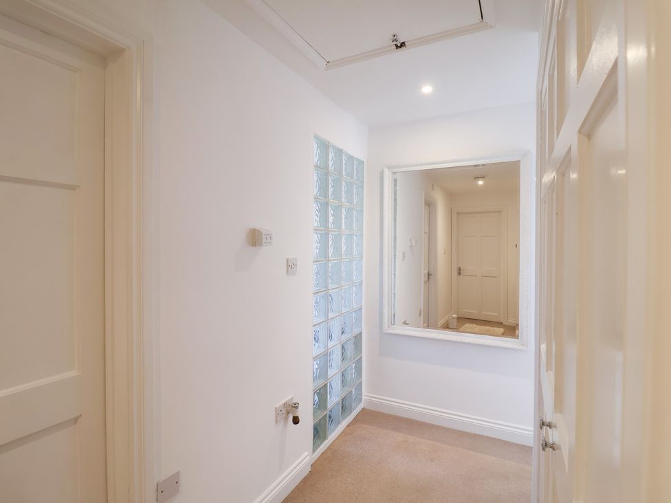 A hallway with a mirror and glass block wall at Three Ways in South Lopham near Garboldisham