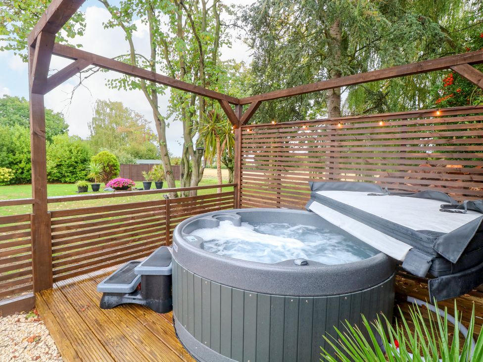 A hot tub on wooden decking in a garden at Three Ways South Lopham near Garboldisham
