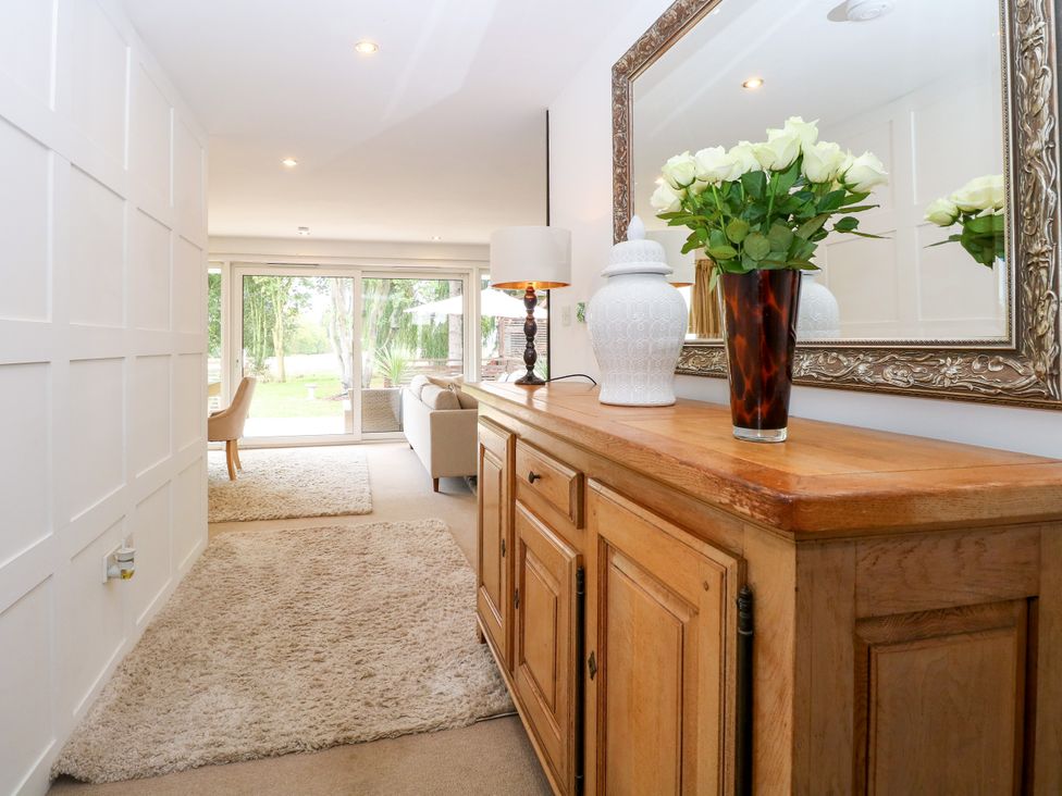 A hallway with a wooden table and flowers at Three Ways South Lopham near Garboldisham
