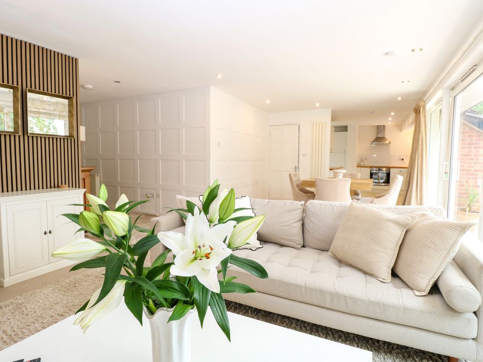 A living room with a sofa and vase of flowers at Three Ways in South Lopham near Garboldisham