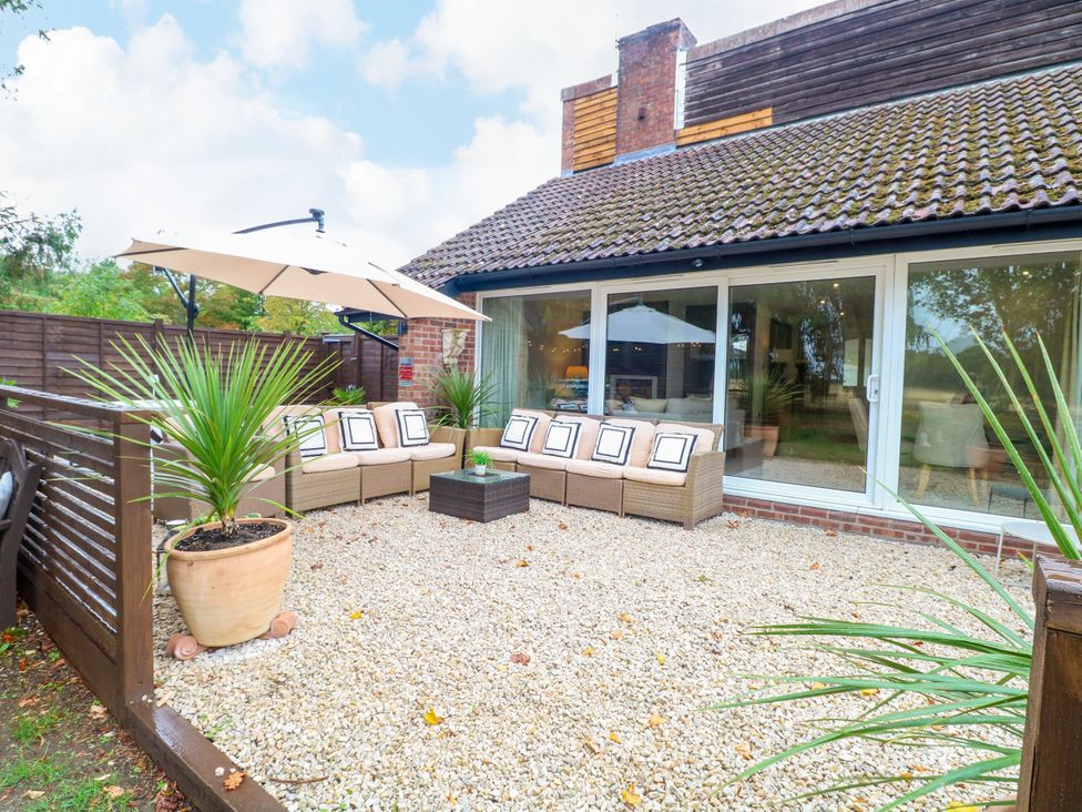 A garden area with a sofa and umbrella at Three Ways South Lopham near Garboldisham