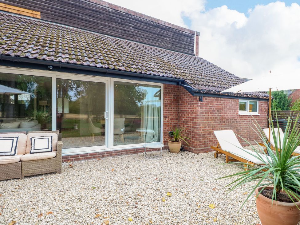 A garden with a sofa and loungers at Three Ways in South Lopham near Garboldisham