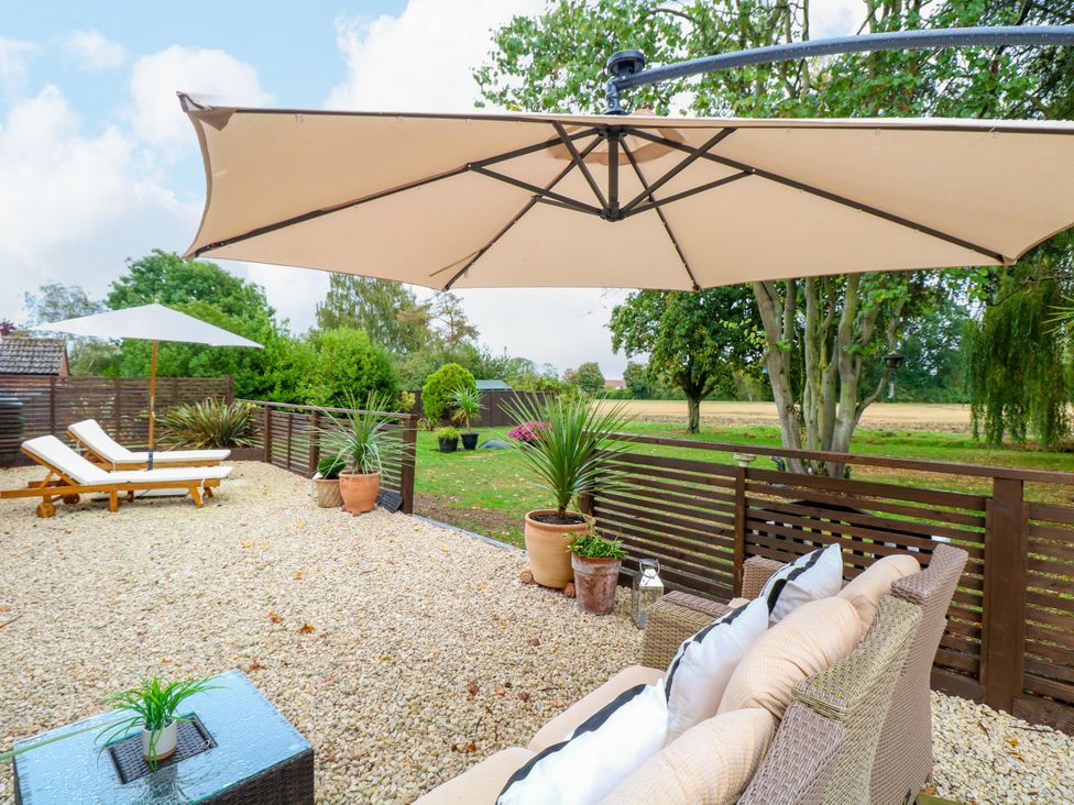 An outdoor seating area with sun loungers and an umbrella at Three Ways South Lopham near Garboldisham