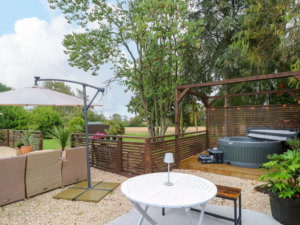 A garden area with a table and chairs and a hot tub at Three Ways in South Lopham near Garboldisham