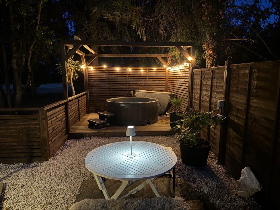 An outdoor area with a hot tub and table at Three Ways South Lopham near Garboldisham