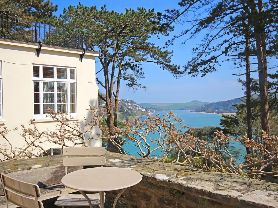 An outdoor area with a table and chairs overlooking water at 4 Ringrone Salcombe