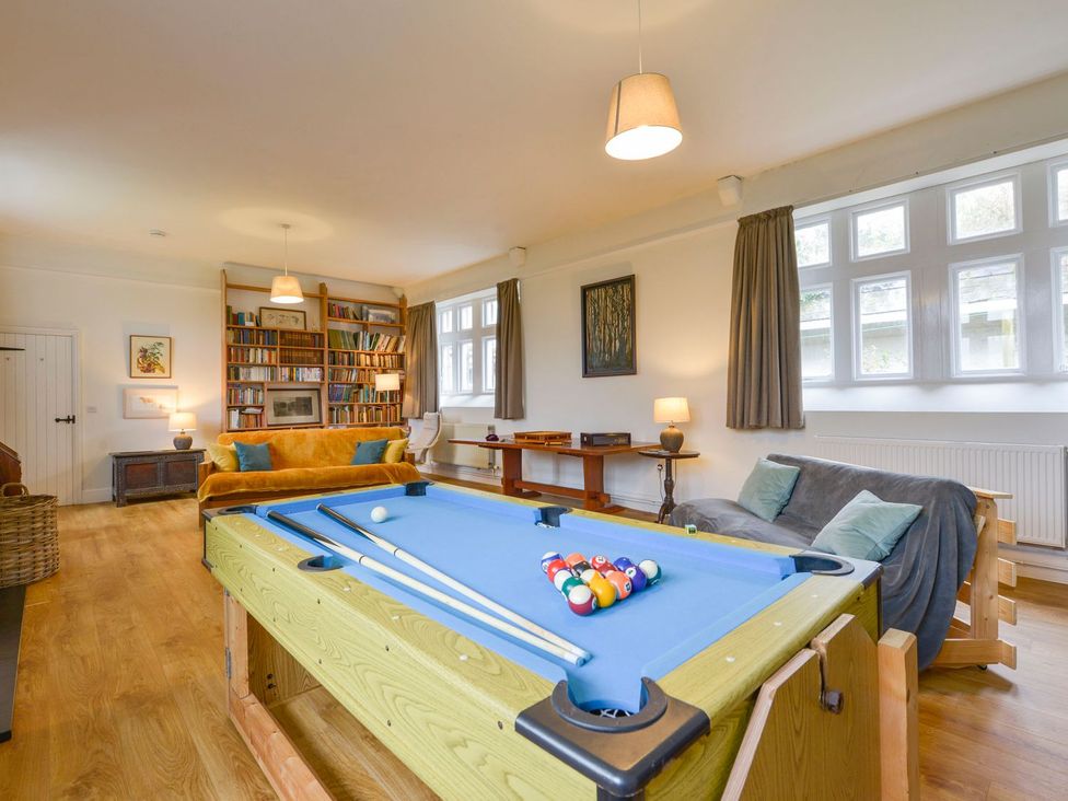 A living room with a pool table and bookshelf at School House in Ivybridge
