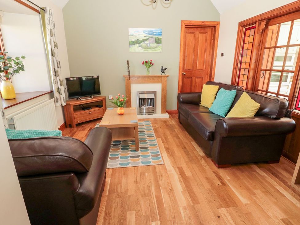 A living room with a sofa, coffee table, and television at Cygnet Cottage in Berwick-upon-Tweed