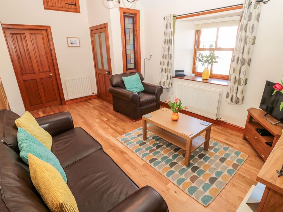 A living room with a sofa, coffee table, and armchair at Cygnet Cottage in Berwick-upon-Tweed