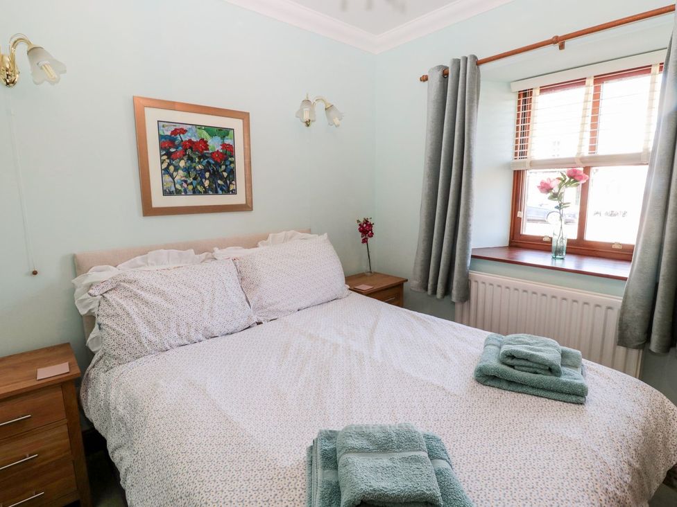 A bedroom with a bed and nightstand at Cygnet Cottage Berwick-upon-Tweed