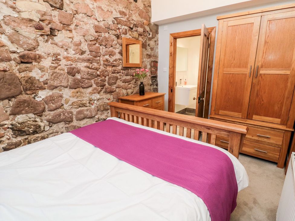 A bedroom with a bed and wooden furniture at Cygnet Cottage in Berwick-upon-Tweed