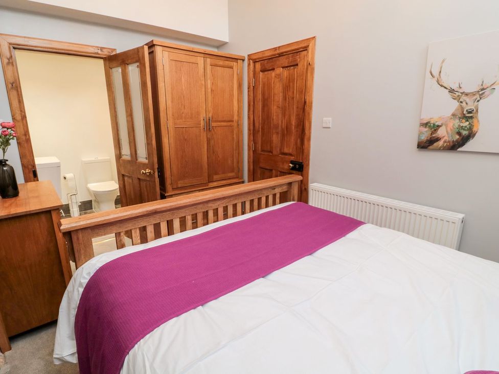 A bedroom with a bed and wardrobe at Cygnet Cottage in Berwick-upon-Tweed