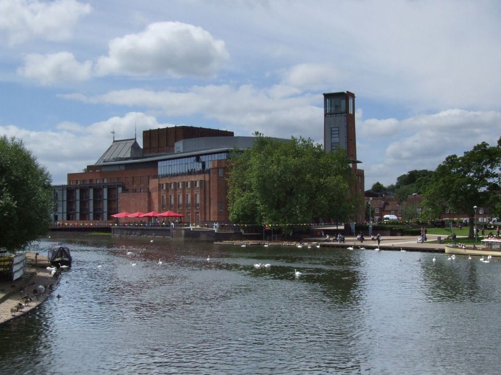 A building by the river with trees and clouds at Glencoe Cottage in Broadway