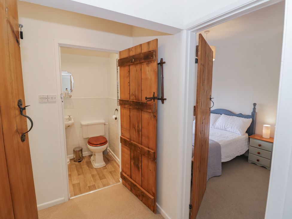 A bathroom and bedroom with wooden doors at Glencoe Cottage in Broadway