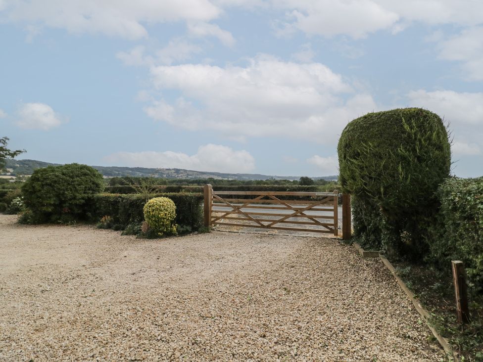 A gravel area with a wooden gate and hedges at Glencoe Cottage Broadway