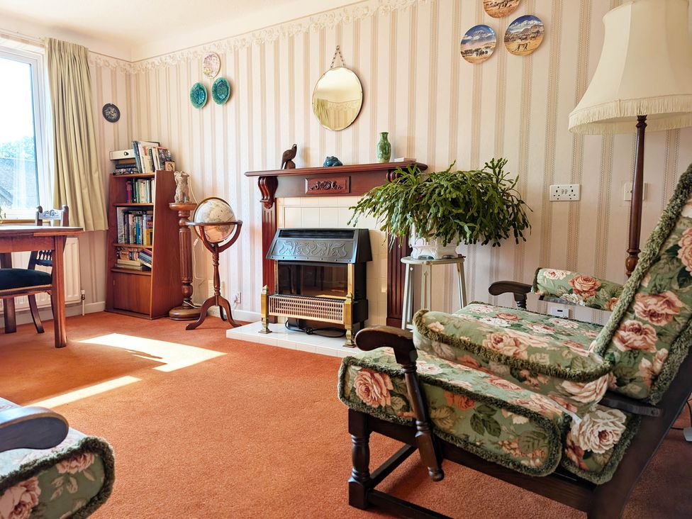 A living room with a fireplace and bookshelf at Roslyn in Romsey