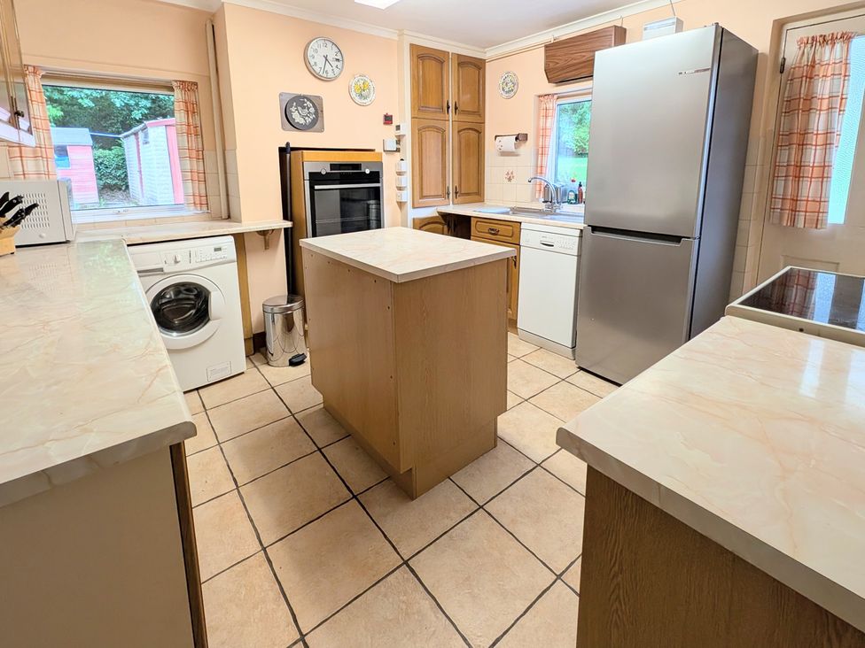 A kitchen with a refrigerator, oven, and washing machine at Roslyn, Romsey
