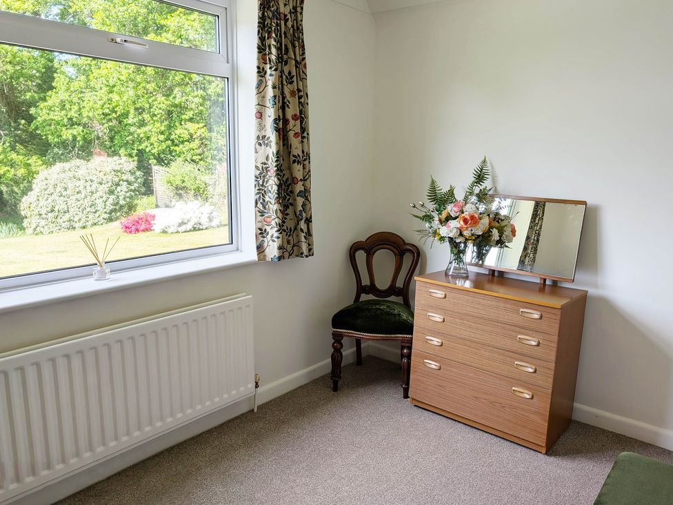 A bedroom with a dresser, chair, and window at Roslyn in Romsey