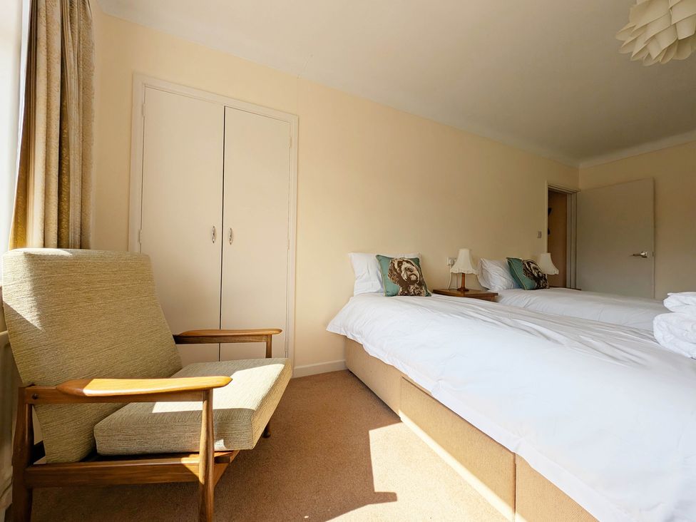 A bedroom with two beds and an armchair at Roslyn in Romsey