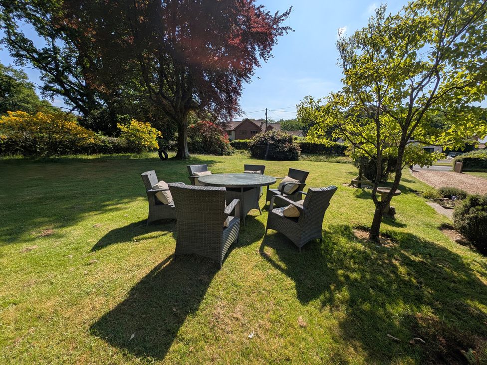 A garden with a table and chairs surrounded by trees at Roslyn in Romsey