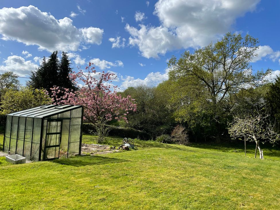 A garden with a greenhouse and trees at Roslyn in Romsey
