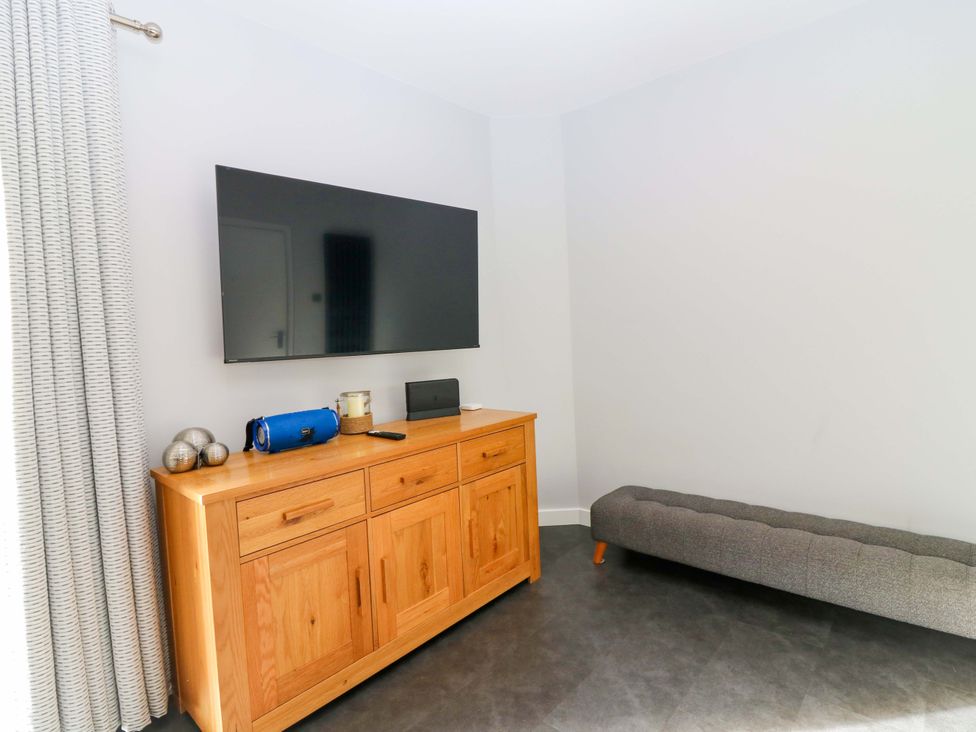 A living room with a television and a cabinet at The Harbour Hoose Stonehaven