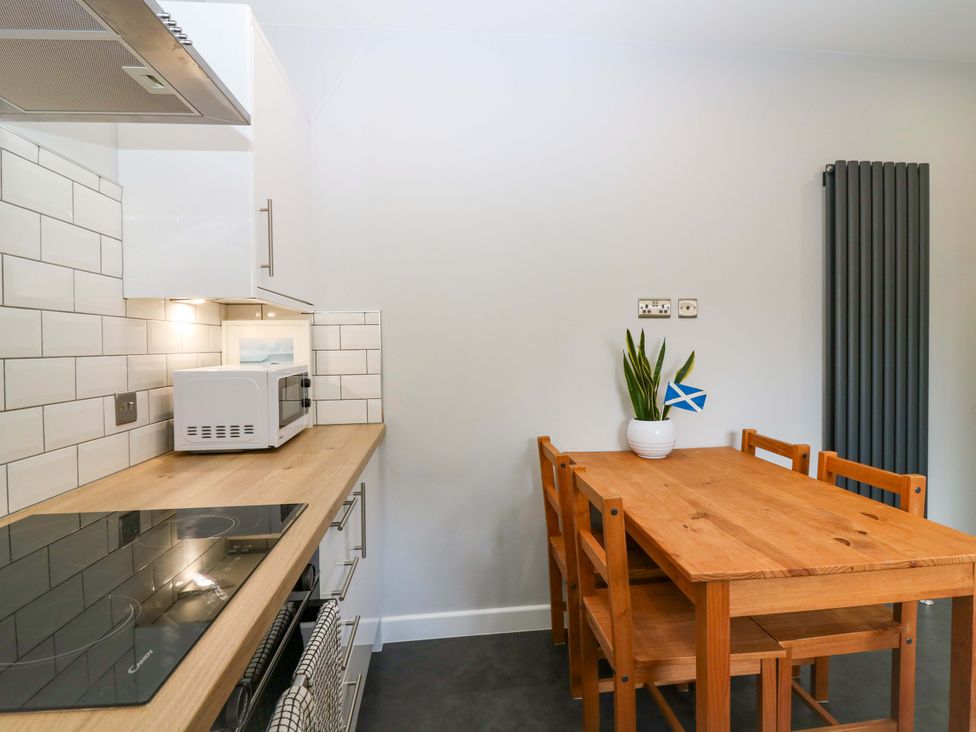 A kitchen with a dining table and microwave at The Harbour Hoose Stonehaven