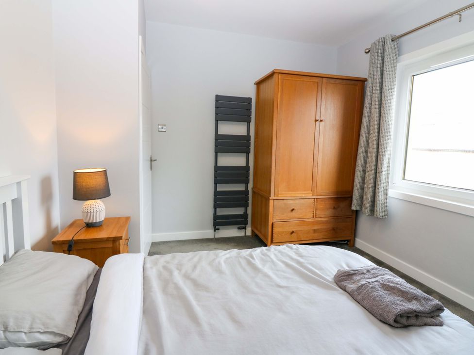 A bedroom with a bed, wardrobe, and lamp at The Harbour Hoose Stonehaven