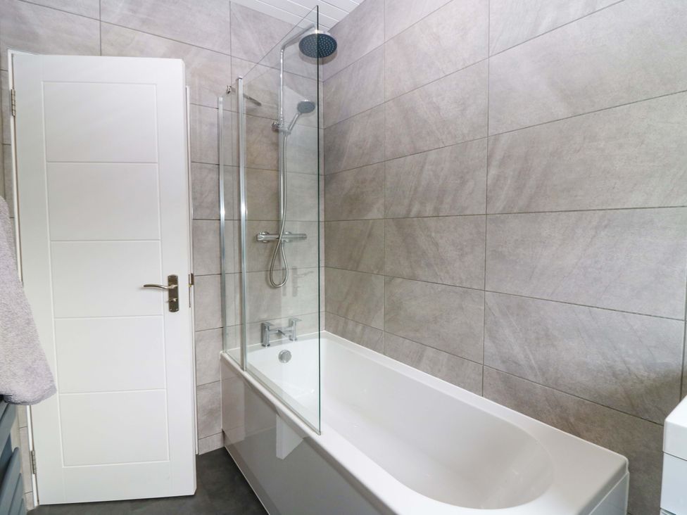 A bathroom with a bathtub and shower features at The Harbour Hoose Stonehaven