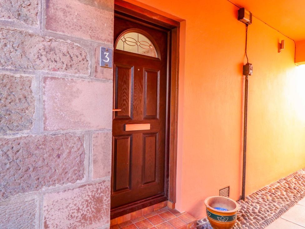 An entrance with a wooden door and flower pot at The Harbour Hoose Stonehaven