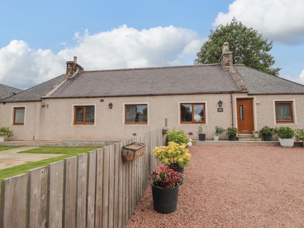 A house with flower pots and a fenced area at Millmoss Cottage