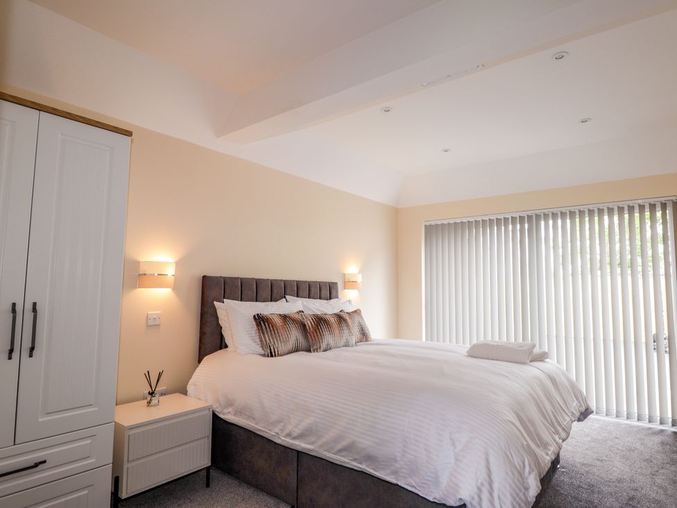 A bedroom with a bed and nightstand at Millmoss Cottage
