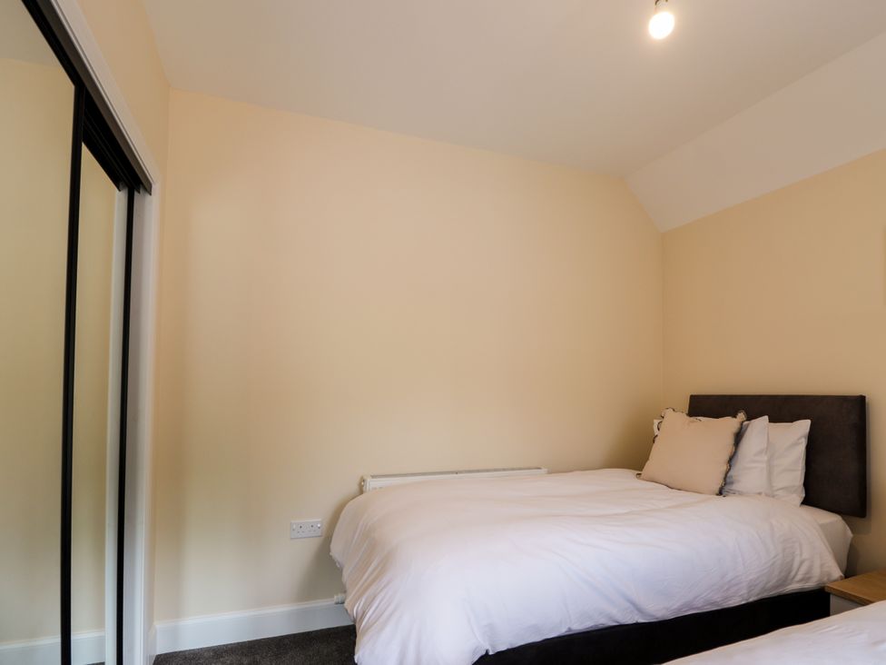 A bedroom with a bed and a mirror at Millmoss Cottage