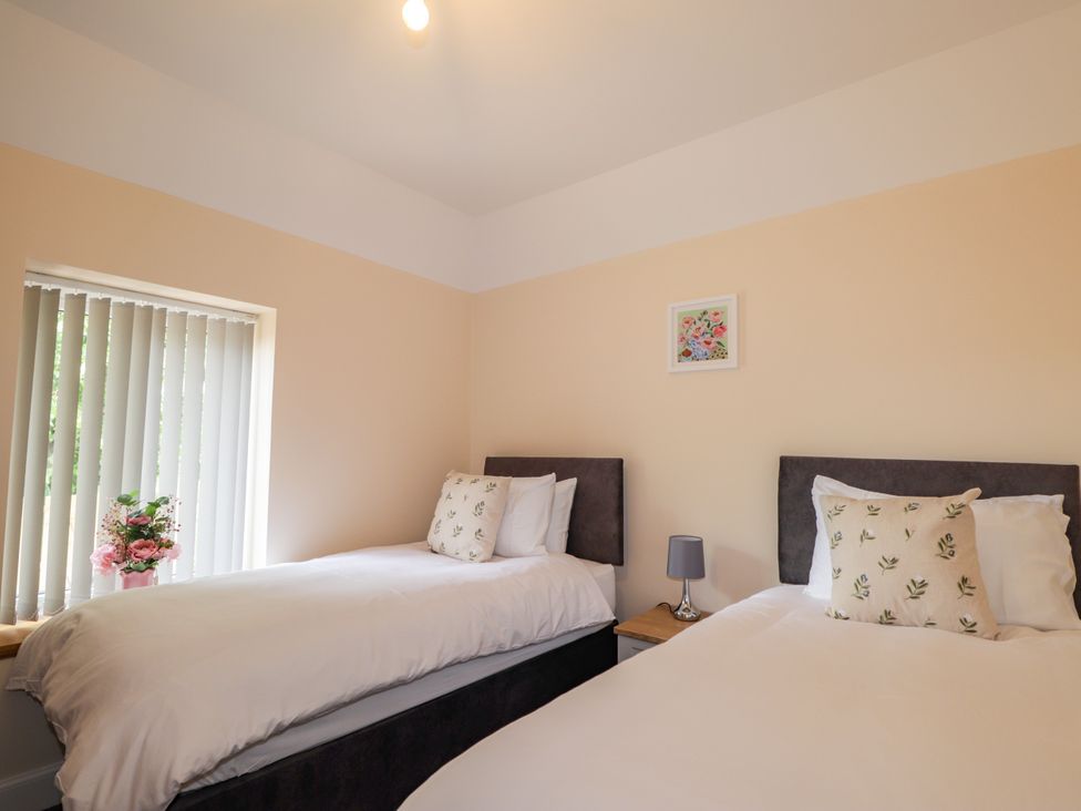 A bedroom with two beds and a window at Millmoss Cottage in 