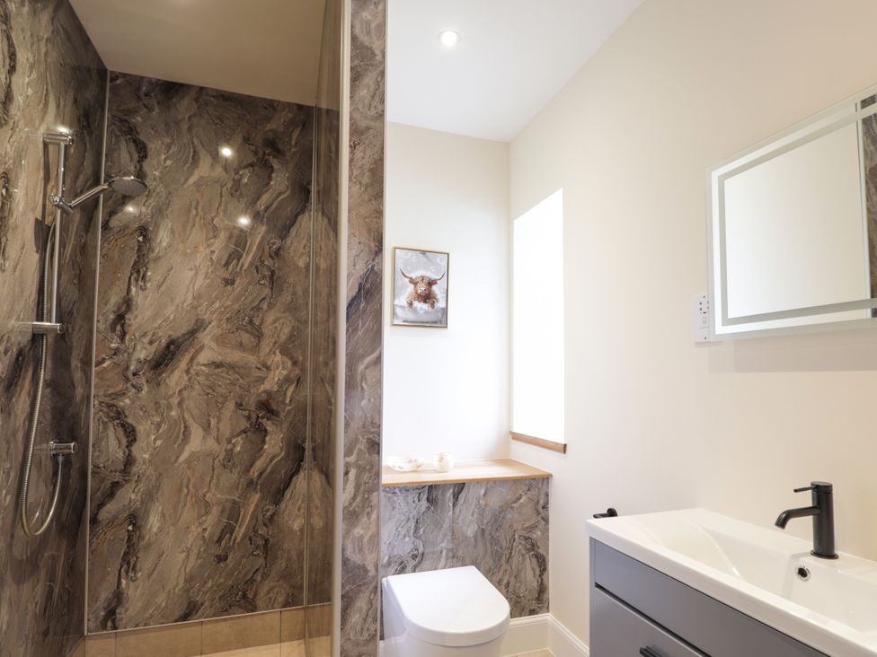 A bathroom with shower, toilet, sink, and wall art at Millmoss Cottage 