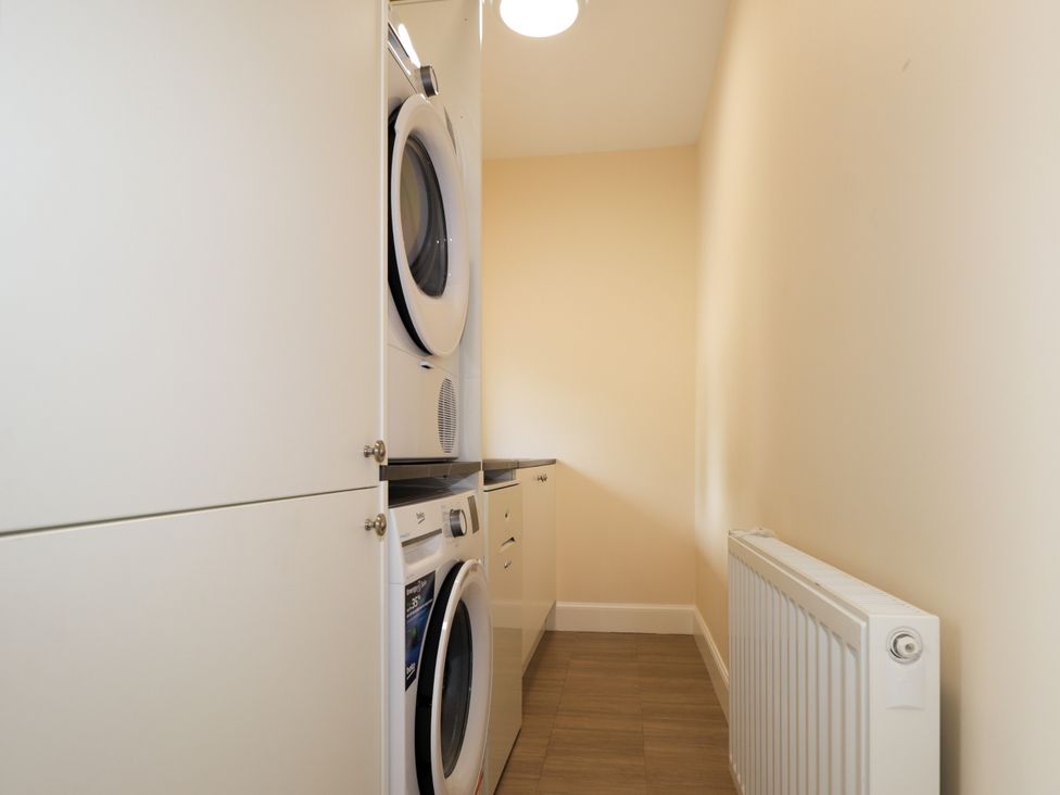 A laundry room with a washing machine, dryer and countertop at Millmoss Cottage