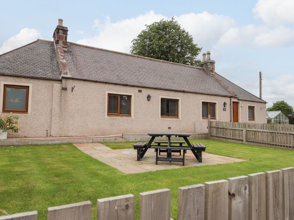 A garden with a picnic table and chairs at Millmoss Cottage in 