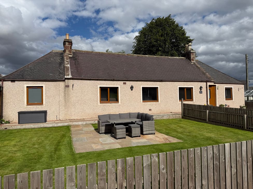 A house with seating area in the garden at Millmoss Cottage Turriff