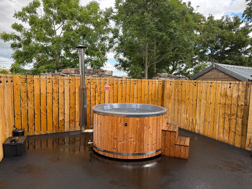 An outdoor area with a hot tub and wooden fence at Millmoss Cottage Turriff