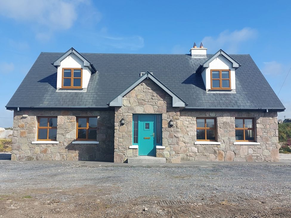 A house with stone facade and a teal door at Tigh Marie