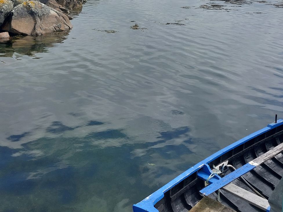 A view of water with a blue boat and rocks at Tigh Marie in 